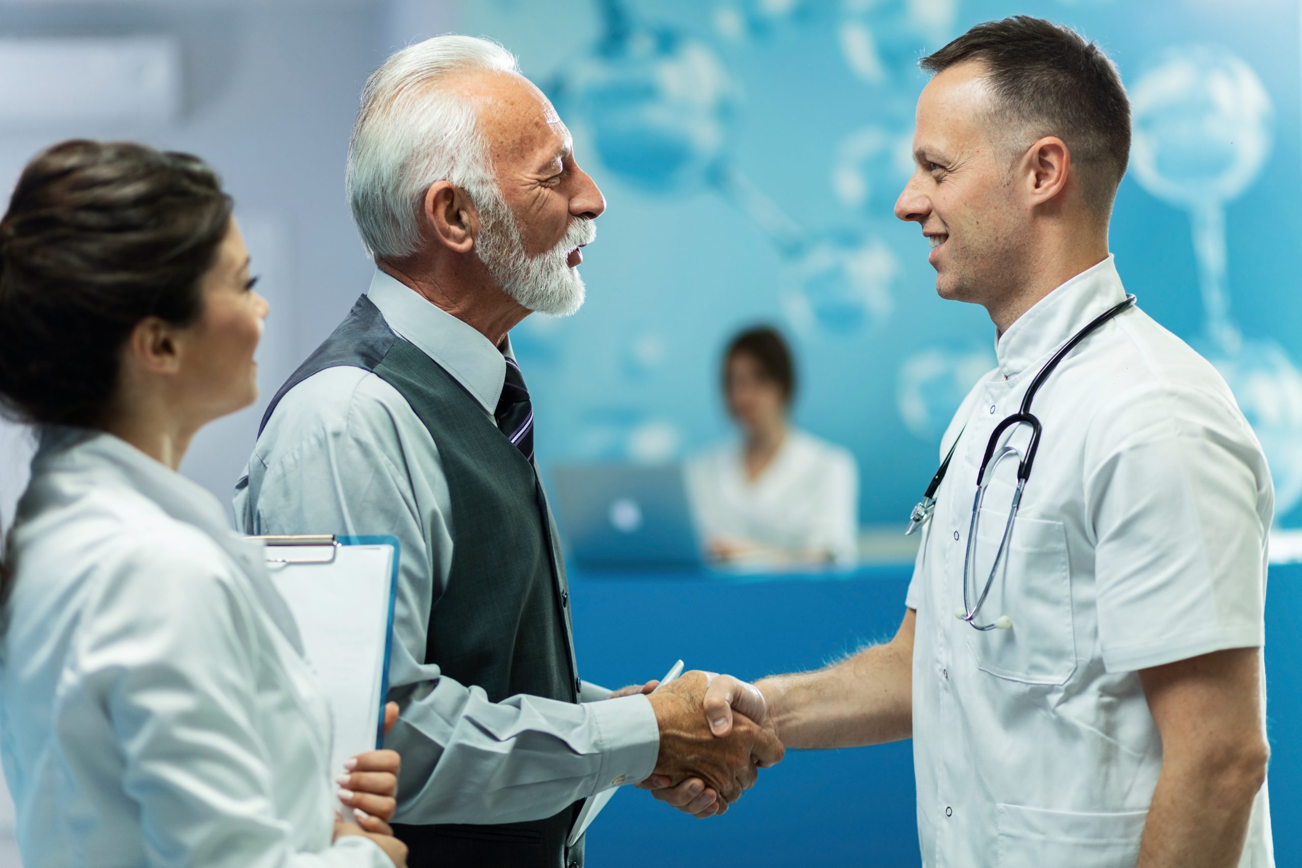 Happy mature businessman shaking hands with doctor in the hospital.